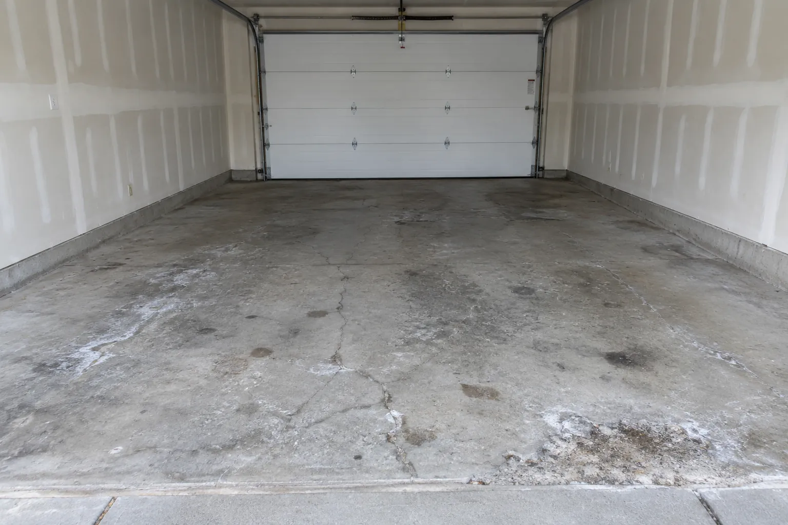 Cracked, stained bare concrete garage floor before coating
